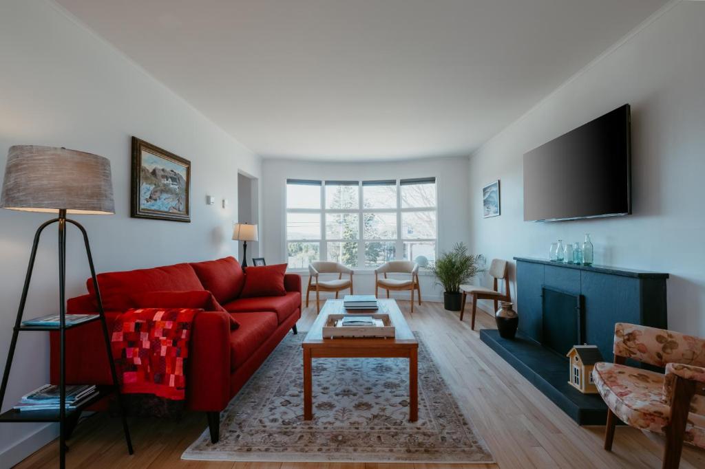 a living room with a red couch and a table at Cherry Lane Cottage | 3 Bed & 2 Bath in Foxtrap