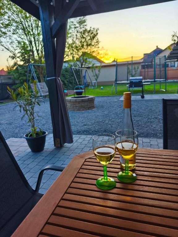 a bottle of wine and two glasses on a wooden table at GRAND HOME Apartman in Sárospatak
