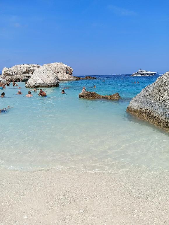 a group of people swimming in the water on a beach at Little paradise apartment with pool in Orosei