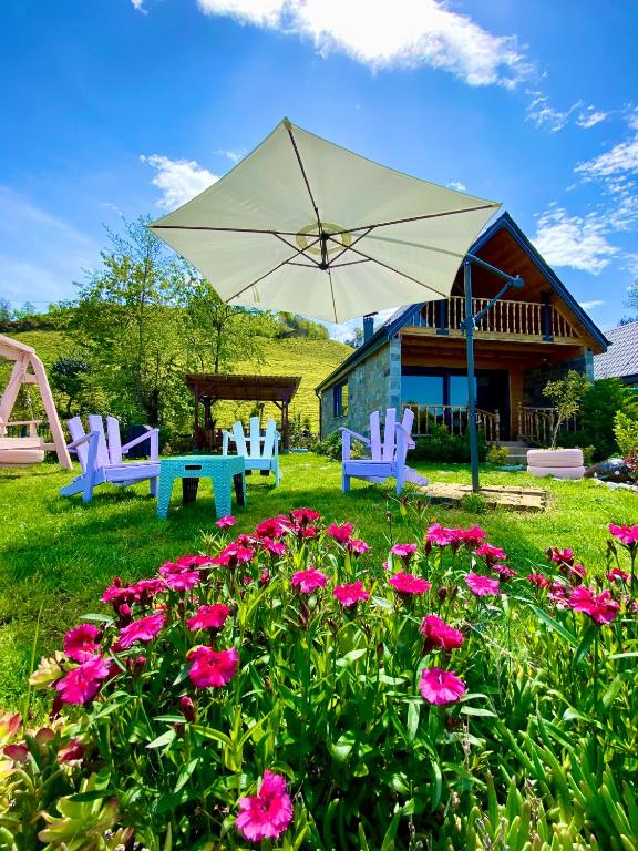 a patio with chairs and an umbrella and flowers at Seyregah Dağ Evi in Ardeşen