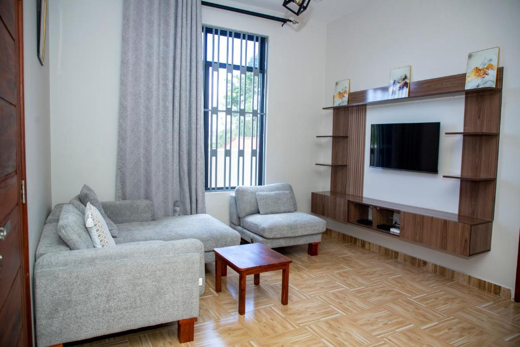 a living room with a couch and two chairs and a tv at Be Home Apartments in Nkoanrua