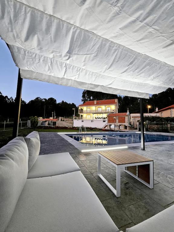 a large white canopy over a pool with a table at Villa Playa Covelo in Pontevedra
