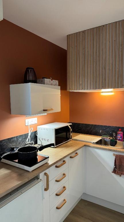 a kitchen with white cabinets and a microwave on a counter at Bagnole de l'Orne Studio in Bagnoles de l'Orne