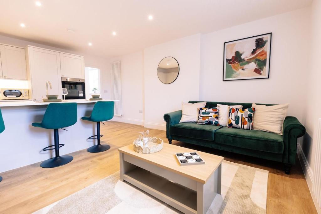 a living room with a green couch and a table at The Spa Town Loft in Buxton