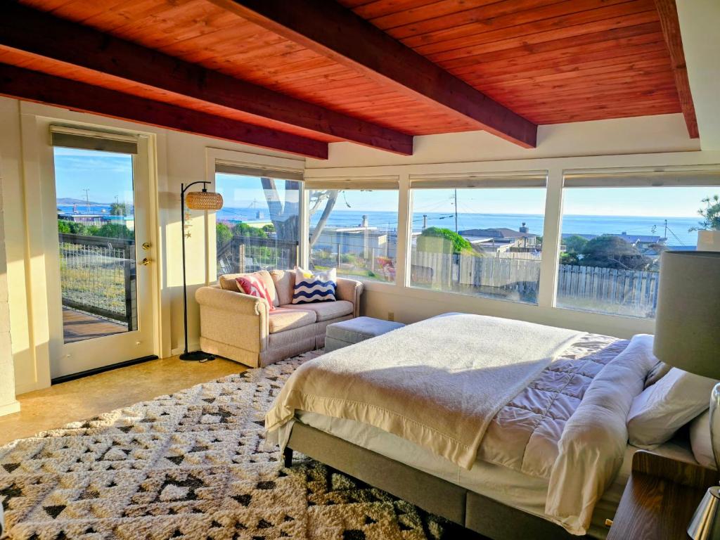 a bedroom with a bed and a couch and windows at Ocean view-Huge backyard-Quiet neighborhood in Bodega Bay
