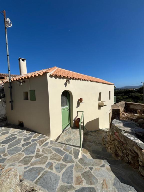 a small white house with a green door at To Ampeli in Potamós
