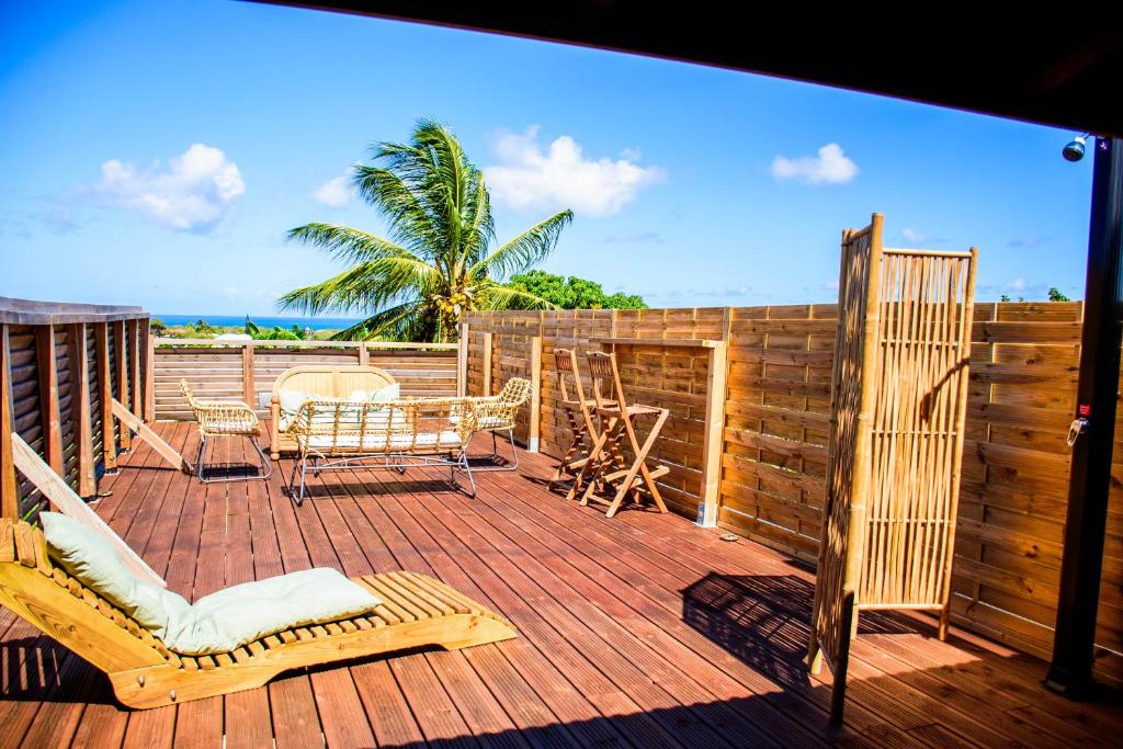 a wooden deck with chairs and a table and chairs at Tootila in Sainte-Rose