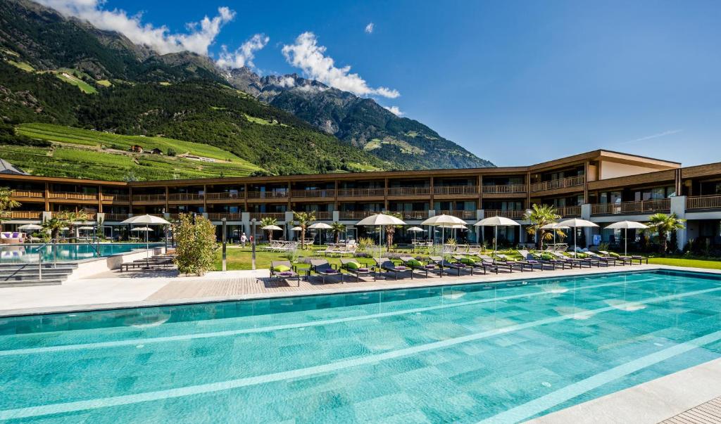 um hotel com piscina e montanhas ao fundo em Hotel Prokulus em Naturno