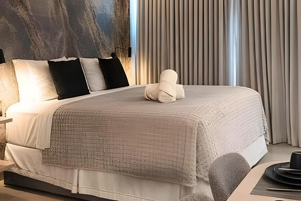 a bedroom with a white bed with a stuffed animal on it at Setai Yatch Garden-Deluxe Praia-Piscina no rooftop in João Pessoa