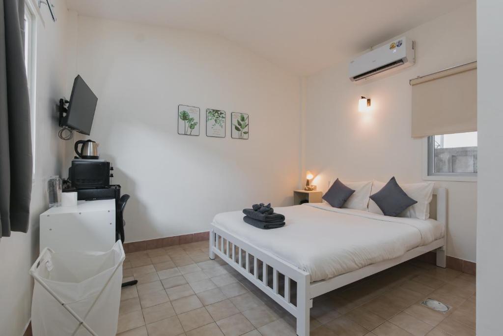 a white bedroom with a white bed and a television at Kavana Kata Residence in Phuket