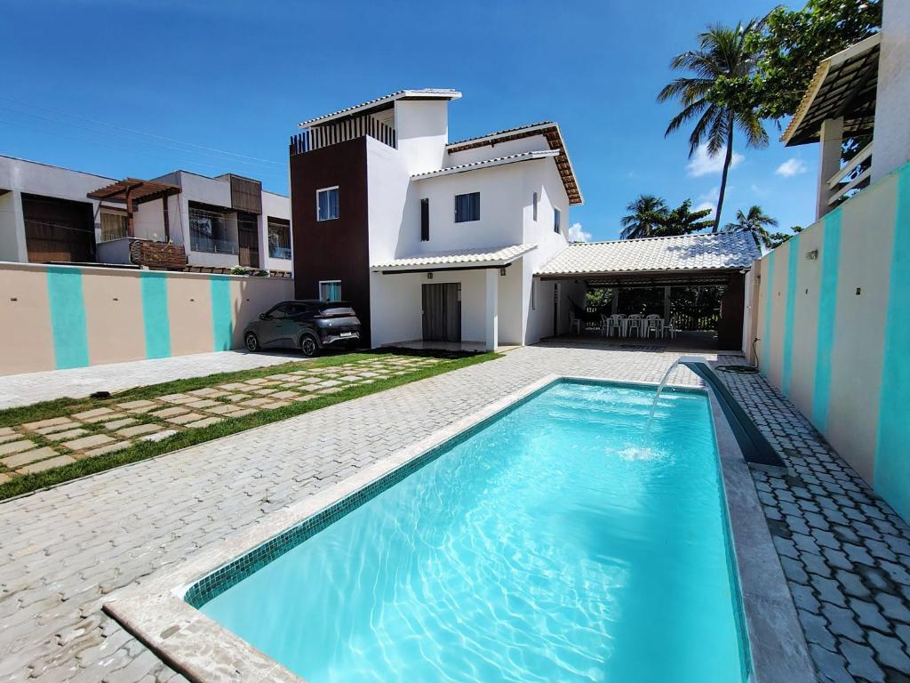 a swimming pool in front of a house at Refúgio Guarajuba, 50m da Praia, Piscina, Recarga EV, área gourmet, churrasqueira in Camaçari