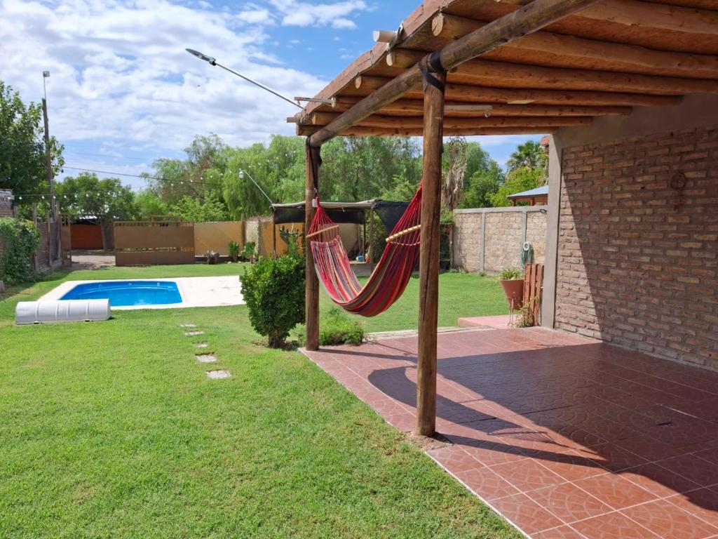 a hammock under a pergola in a backyard at Osvaldo Day Cabin with Pool in Albardón