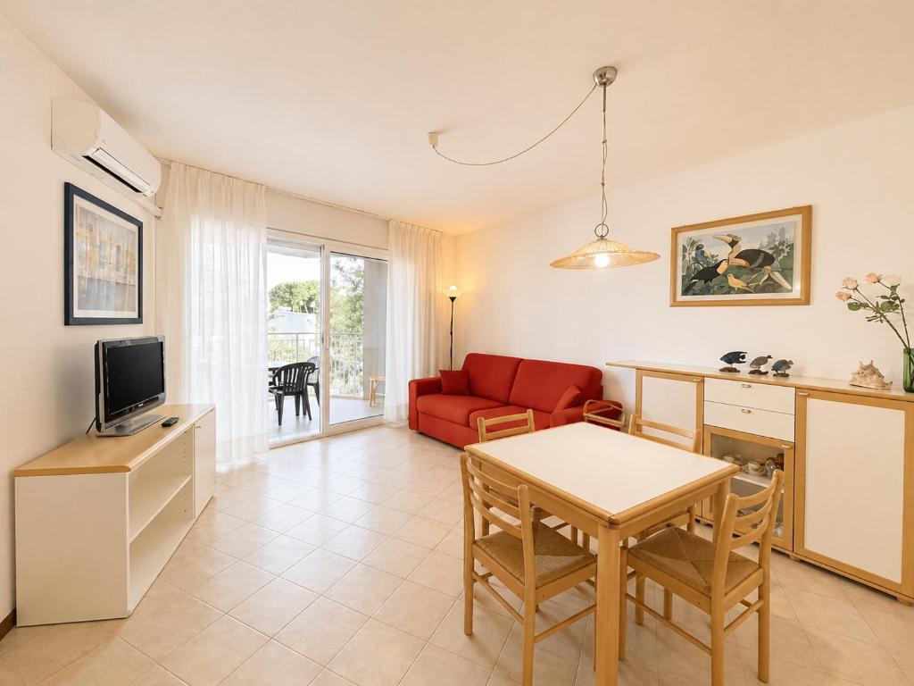a living room with a red couch and a table at Appartamento Eunoia I TerraceParking&AC in Lignano Sabbiadoro