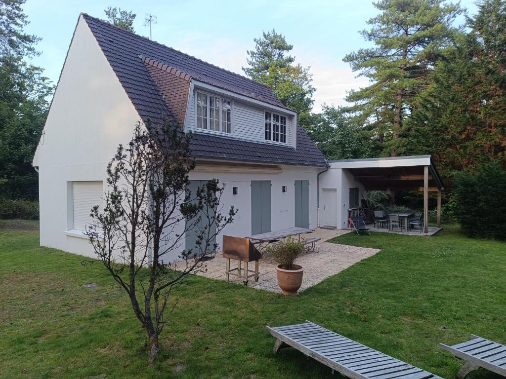 a white house with a bench in the yard at Maison des bois in Neufchâtel-Hardelot