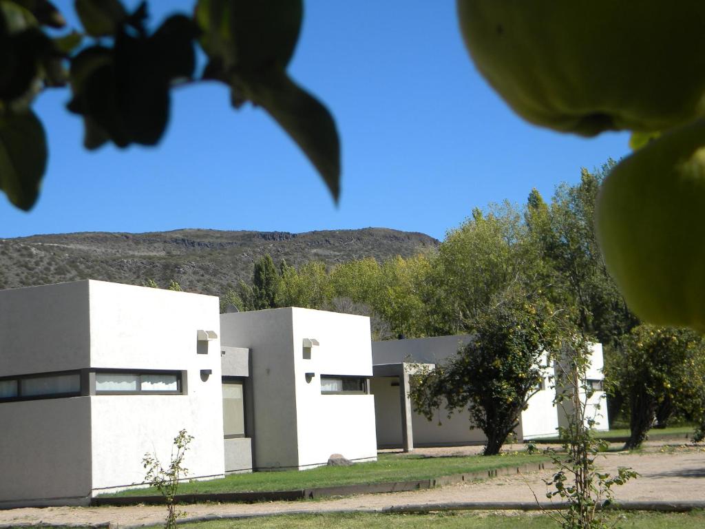 a white building with trees and mountains in the background at Membrillar suites de Montaña in Valle Grande