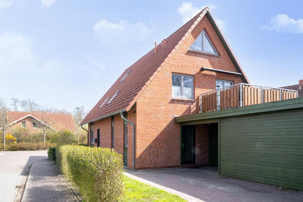 a brick house with a gambrel roof and a garage at Dünenhus Appartement Dünenhus in Böhl