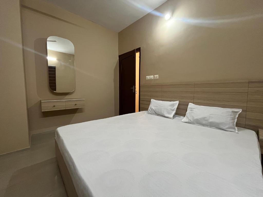 a bedroom with a large white bed and a mirror at S S Apartment in Kannur