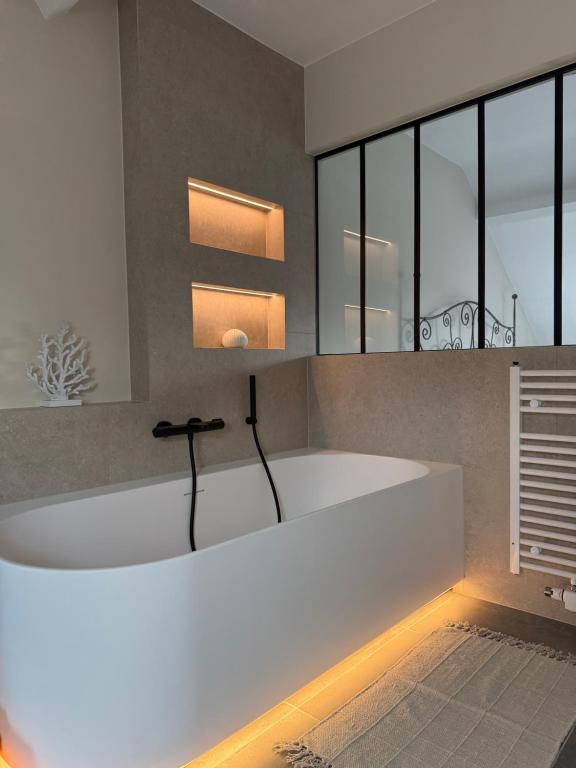 a large white bath tub in a room with windows at La Parenthèse des Charmes in Andenne