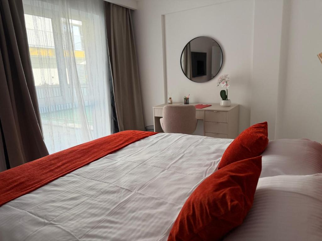 a bedroom with a bed with red pillows and a mirror at IDDA Concept 1 in Târgu-Mureş