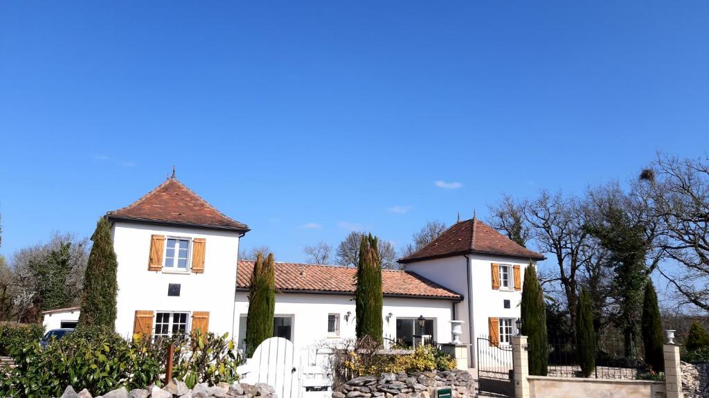 a large white house with a fence and trees at La bâtisse a deux tours in Lalbenque