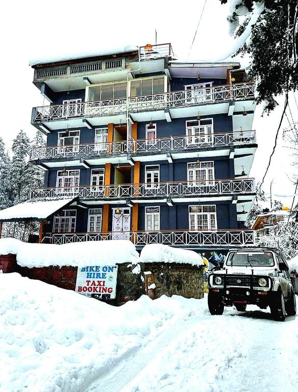 a snow covered building with a car parked in front of it at Casa Nova in Manāli