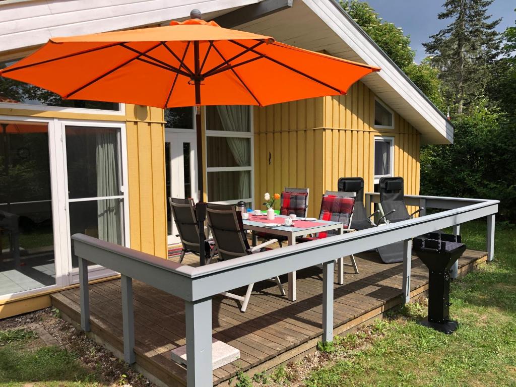 an orange umbrella on a deck with a table and chairs at Seeschwalbe 240 in Mirow