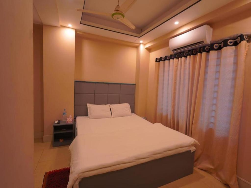 ein Schlafzimmer mit einem weißen Bett und einem Fenster in der Unterkunft Sylhet Hotel Grand Usman in Sylhet