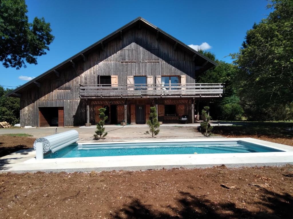 a large barn with a pool in front of it at LES DAMES DE LA SAUGIAT in Le Fied