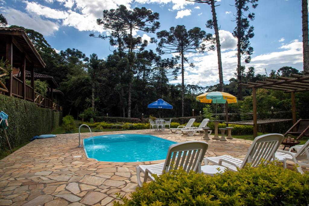 a pool with chairs and umbrellas in a yard at Pousada Recanto do Pico in Santo Antônio do Pinhal