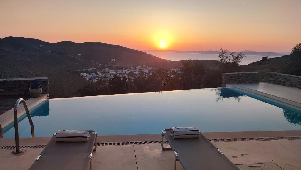 a swimming pool with a sunset in the background at Cycladic Stone House with Pool & Sunset Views in Gialiskari