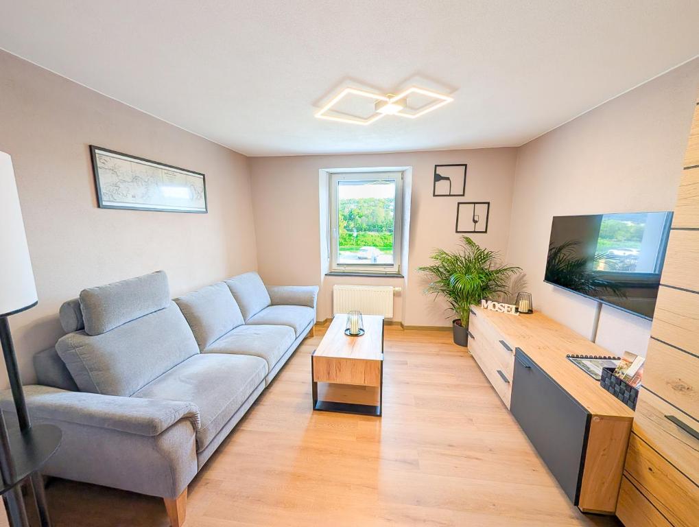 a living room with a couch and a flat screen tv at Ferienwohnung MoselVino in Lieser