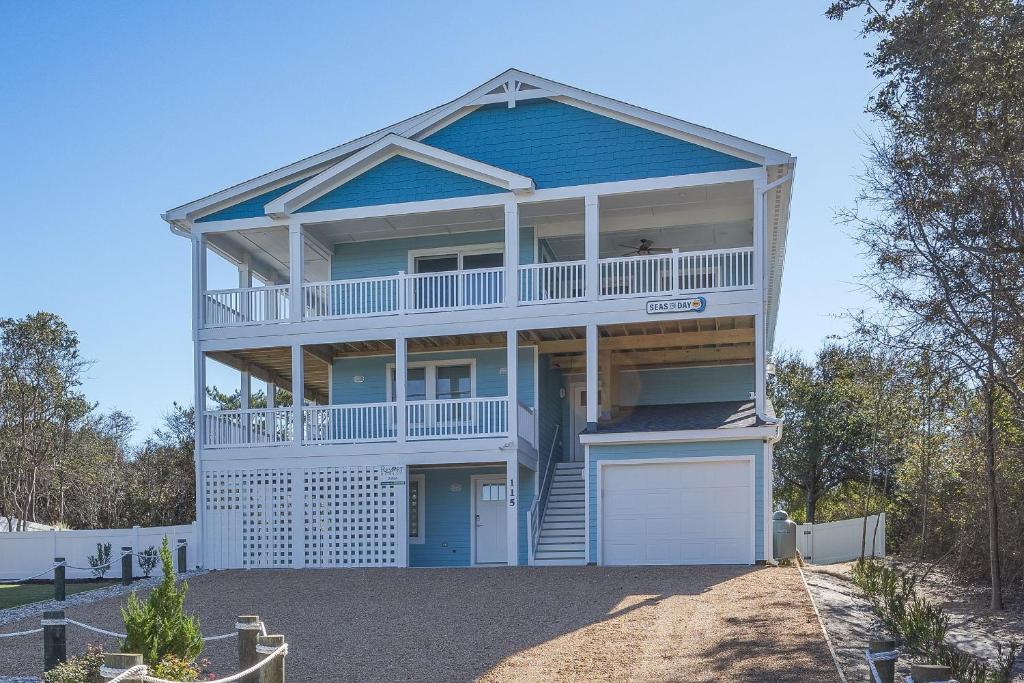 a large blue house with a garage in front of it at 2934 - Seas the Day in Duck