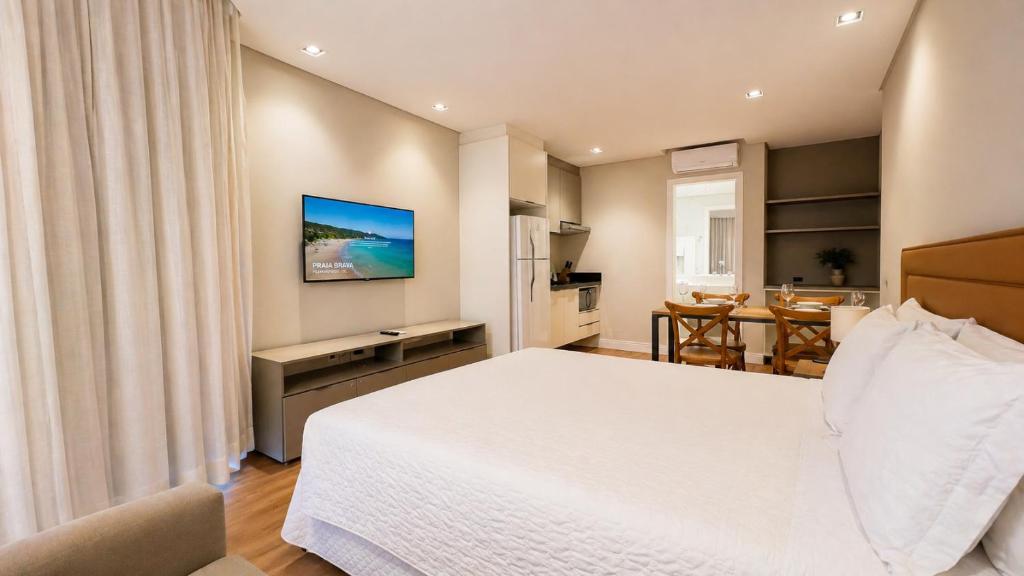 a bedroom with a large white bed and a table at Hotel Praia Brava in Florianópolis