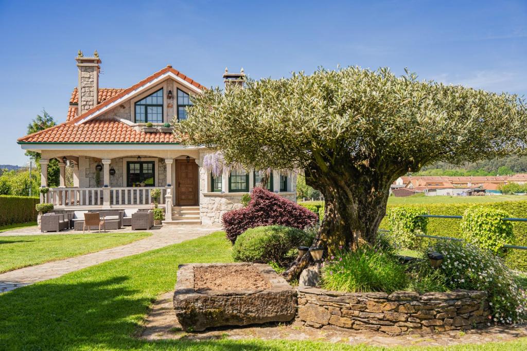 a house with a tree in the front yard at Casa Xardín in O Pedrouzo