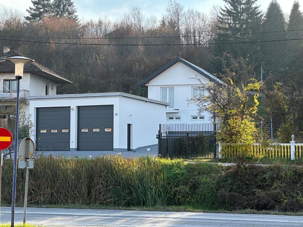 a white house with two garage doors on a street at Comfort Days in Gladno Polje