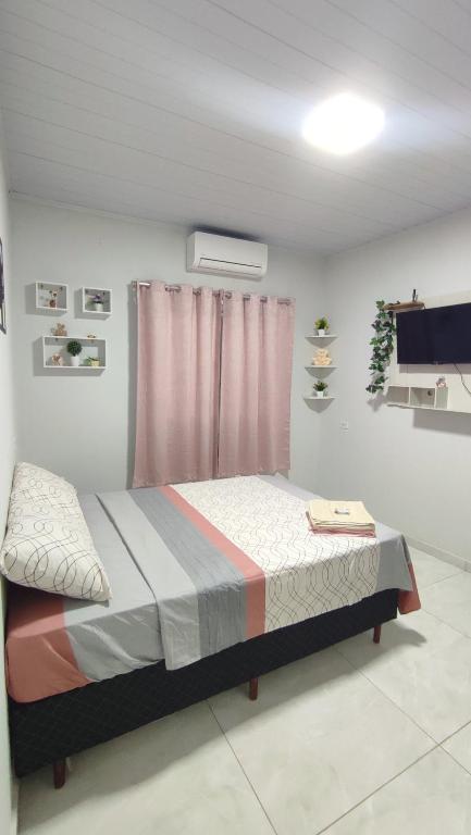 a bedroom with a bed in a room with a tv at Quarto Casal Com AR Condicionado e Banheiro Privativo in Guaíra