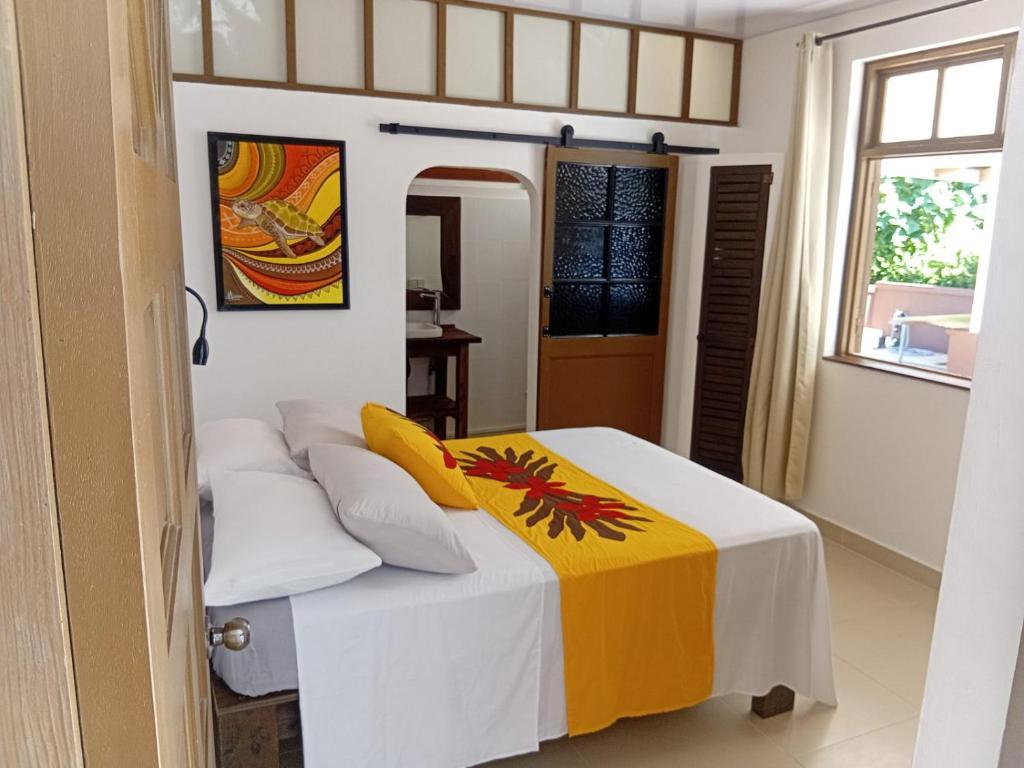 a bedroom with a bed with a yellow and white blanket at Aremiti - Fare Orotia in Taputapuapea