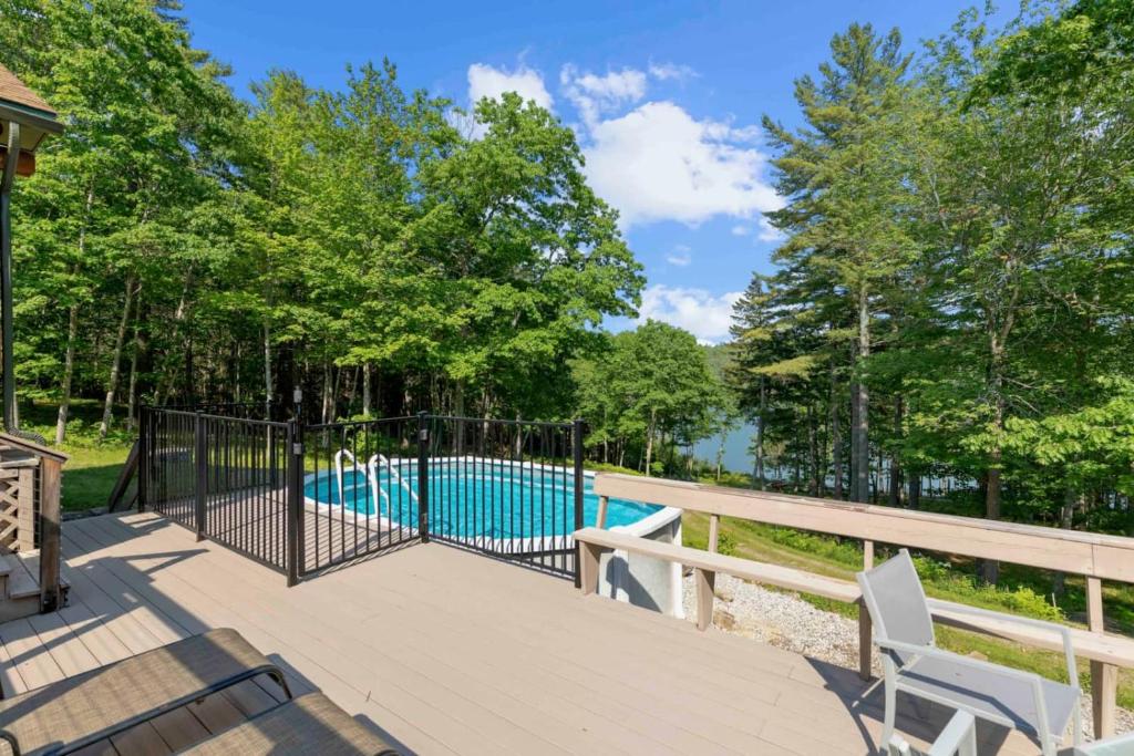 a deck with a pool and two chairs at Shimmering River Retreat in Edgecomb