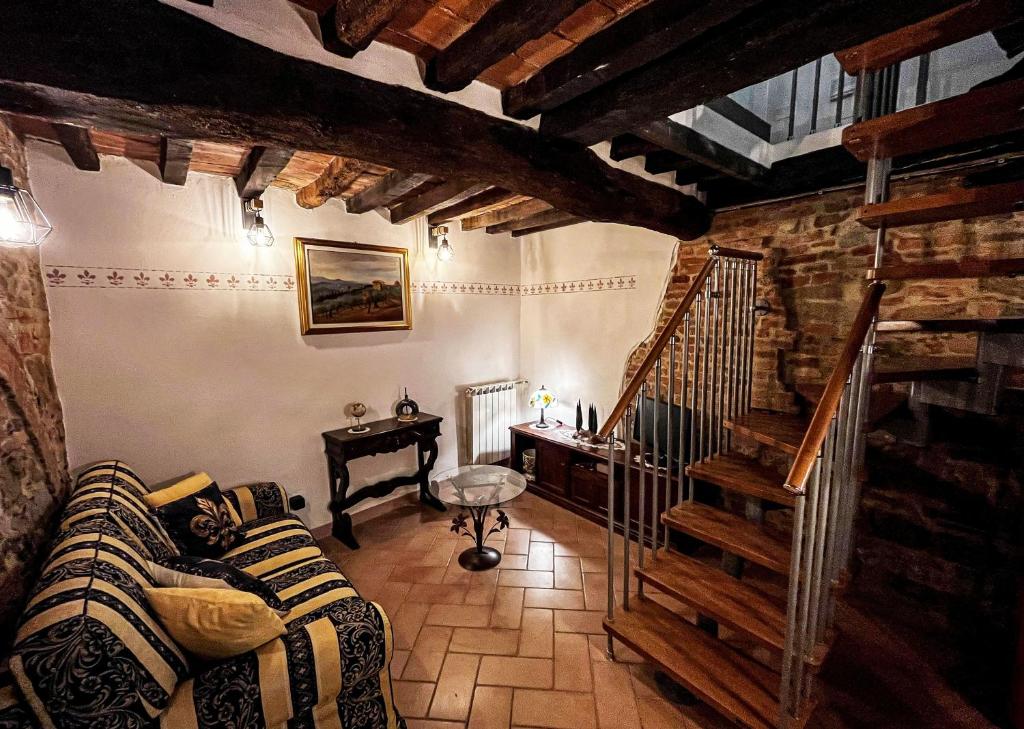 a living room with a couch and a staircase at Dimora del Campanile in Torrita di Siena
