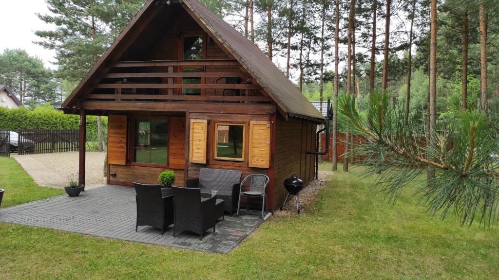 a small wooden cabin with a table and chairs at Domek Pod Sosnami in Kuźnica Nowa