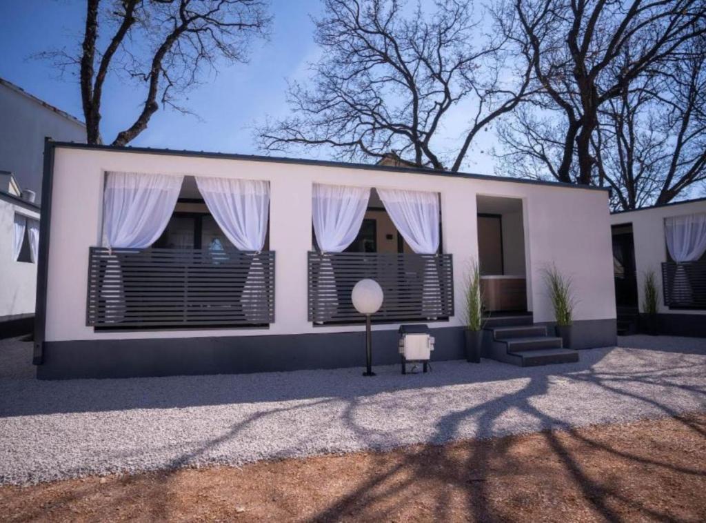 a white house with black shuttered windows and stairs at Lux Mobile Homes Vodice in Vodice