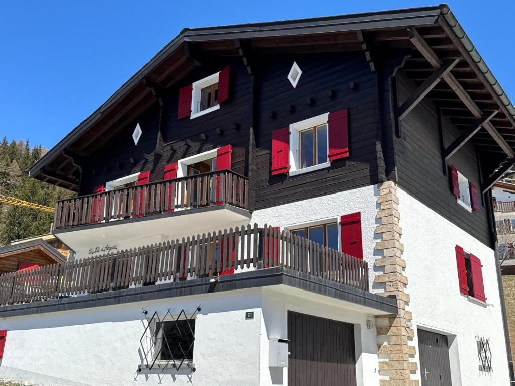a house with a balcony with red shutters at Chalet Le Nid D'argent - Dans la nature in Crans-Montana