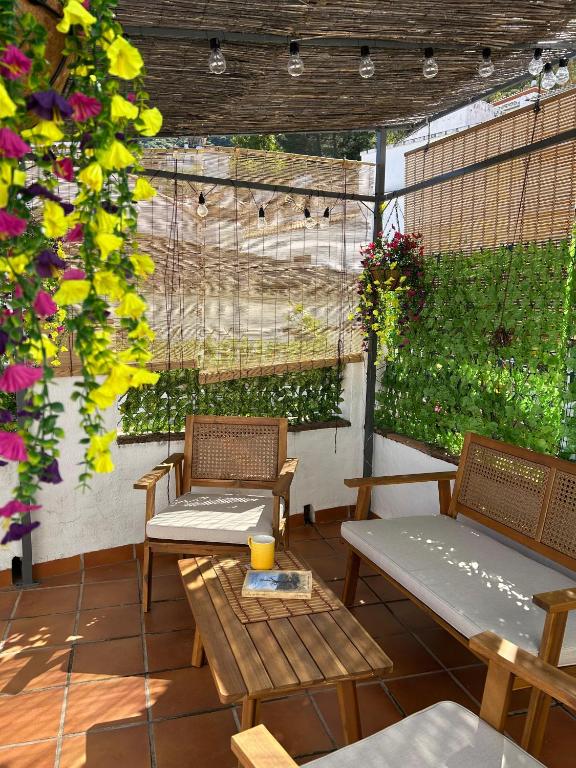 two chairs and a table on a patio with flowers at Casa Solana in Benadalid