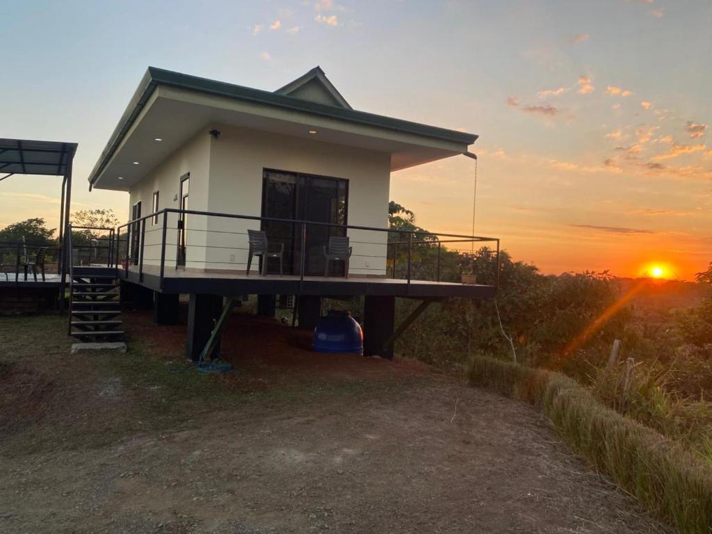 a small house with a sunset in the background at Villa Kiskadee - Beautiful Mountain Views with Private Pool in Quepos