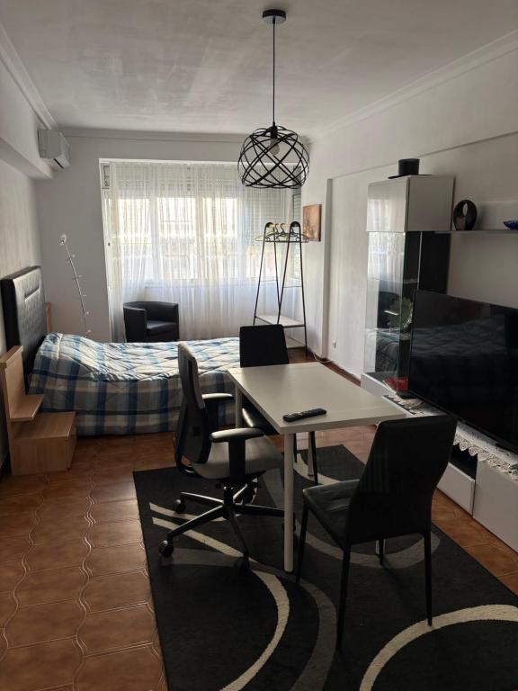 a room with a table and chairs and a bed at Quarto de Casal Acolhedor in Laranjeira