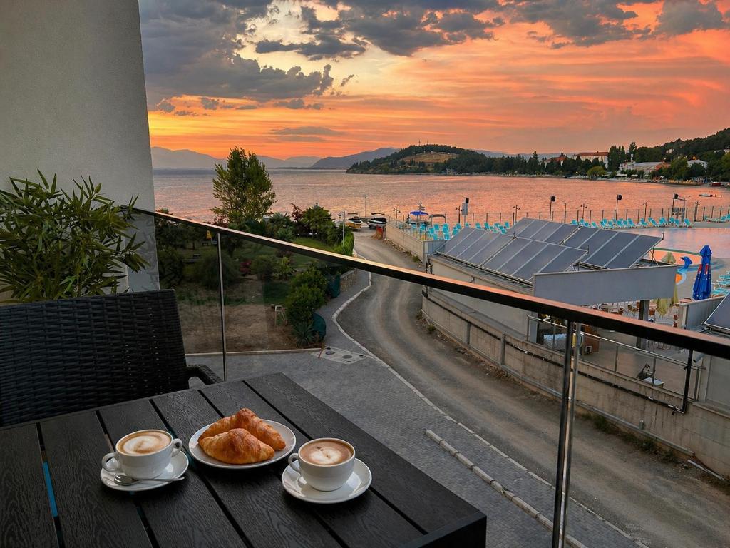 a table with a plate of croissants and cups of coffee at Lungolago Apartment Ohrid in Ohrid