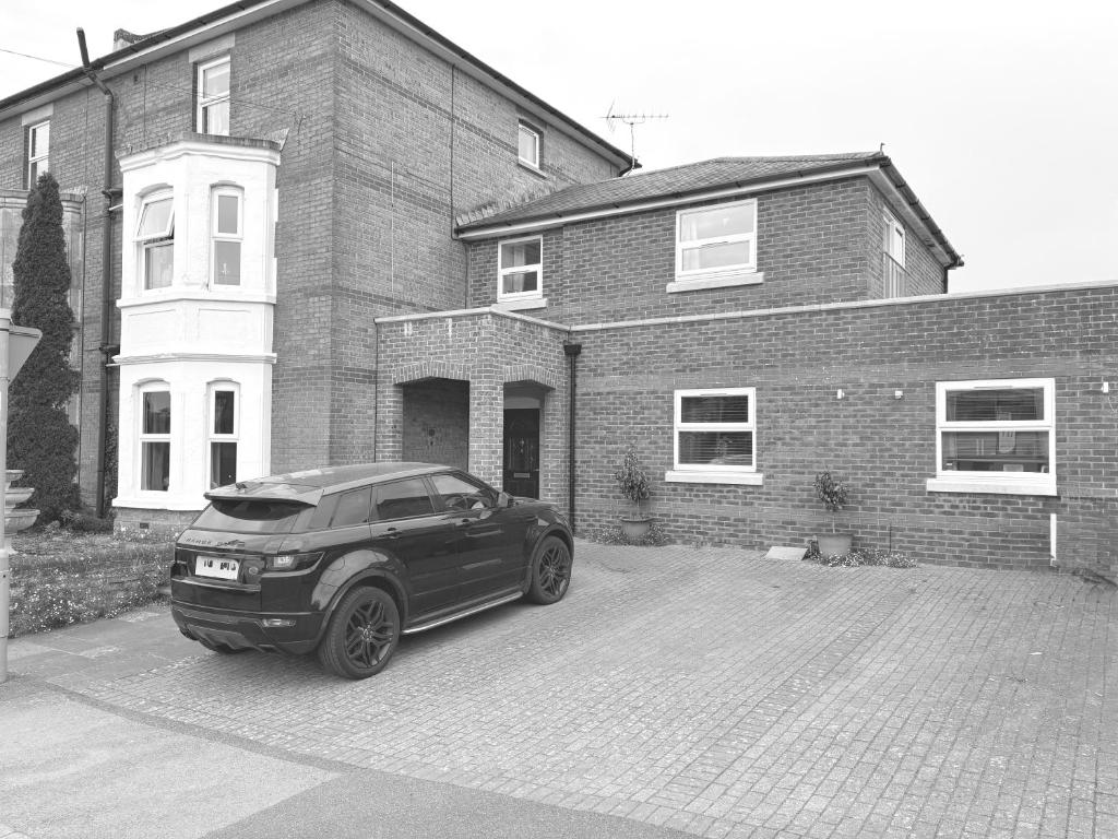 a car parked in front of a brick house at Baytree Guest House in Dorchester