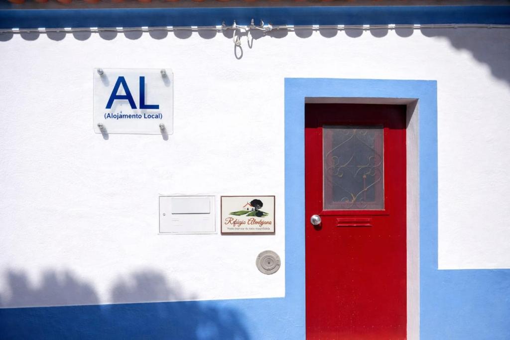 a building with a red door and a sign on it at Refúgio Alentejano in Alandroal