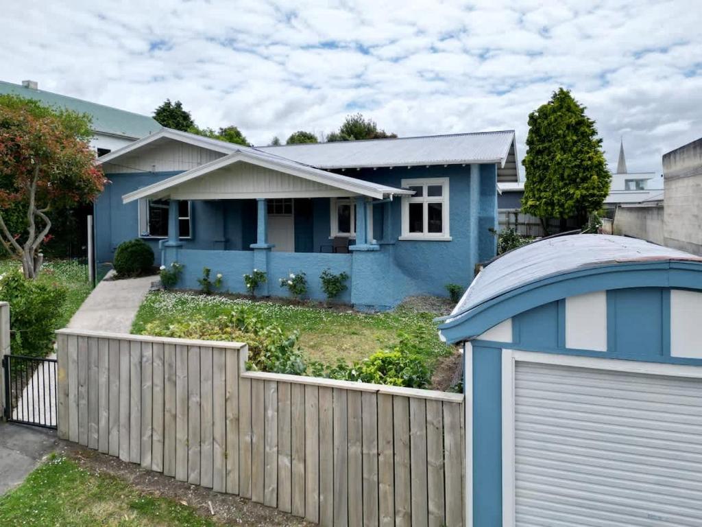 a blue house with a fence and a gate at Welcome To Wansbeck in Oamaru