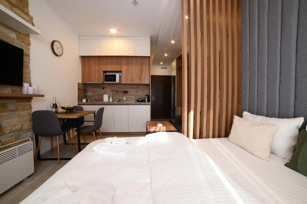 a bedroom with a large white bed and a kitchen at Kopaonik Mountain Retreat in Cajetina